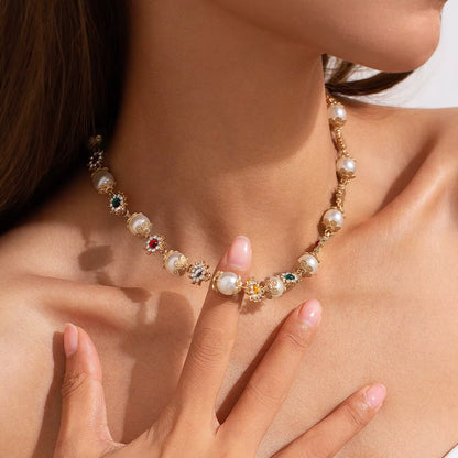 Close-up of woman wearing gold necklace with pearls and multicolored gemstone accents