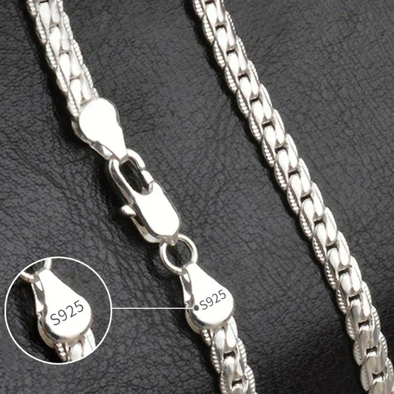 Close-up of sterling silver chain necklace with S925 stamp on clasp against black background