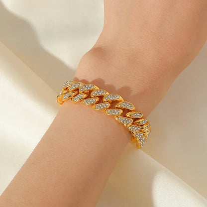 gold chain link bracelet with clear crystals on wrist against soft white fabric background