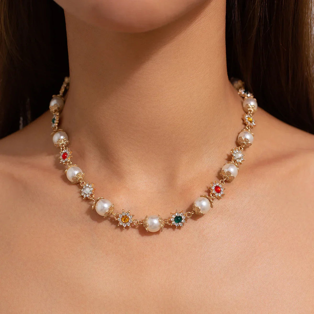 Elegant pearl and gemstone necklace with gold floral settings worn on neck