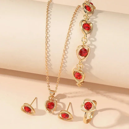Gold jewelry set with red heart-shaped gemstones including necklace, bracelet, earrings, and ring