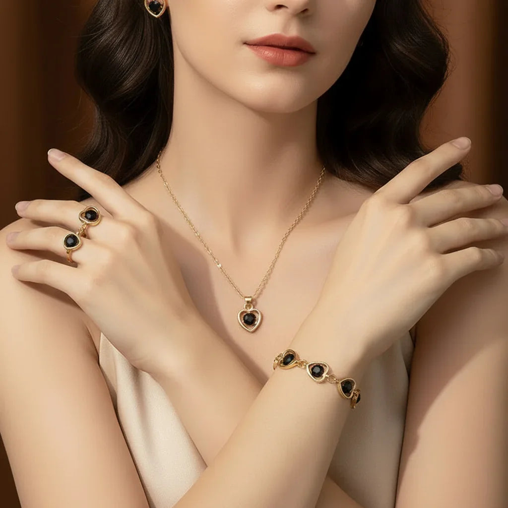 Woman wearing gold jewelry set with black heart-shaped stones including earrings, rings, necklace, and bracelet