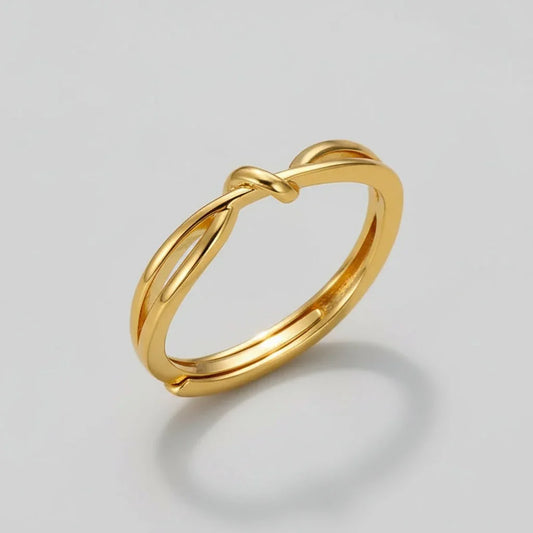 Elegant gold knot ring with simple, sleek design on plain light background